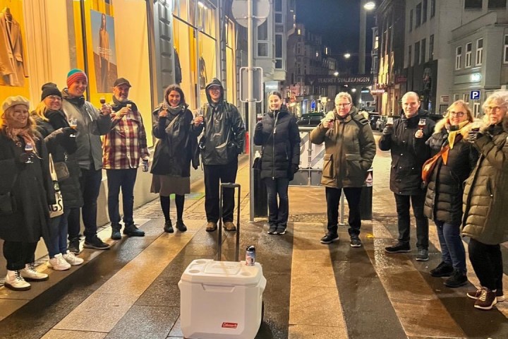a group of people standing on a sidewalk waiting for a train